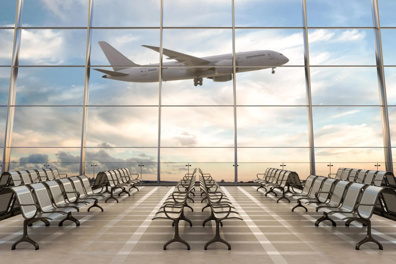 Airport departure lounge with a passenger jet visible through large windows