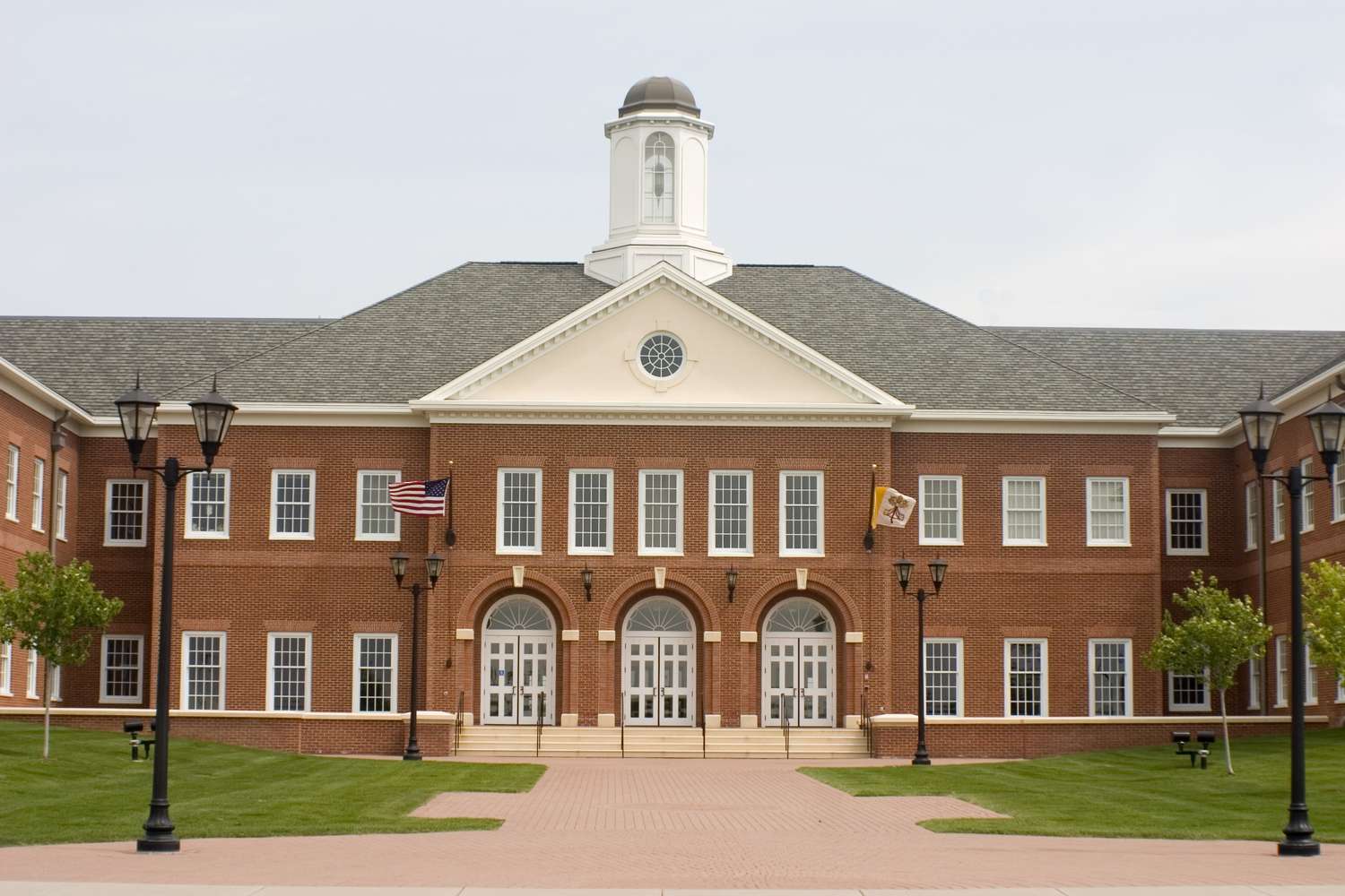 Brick school building with a clock tower and lawn
